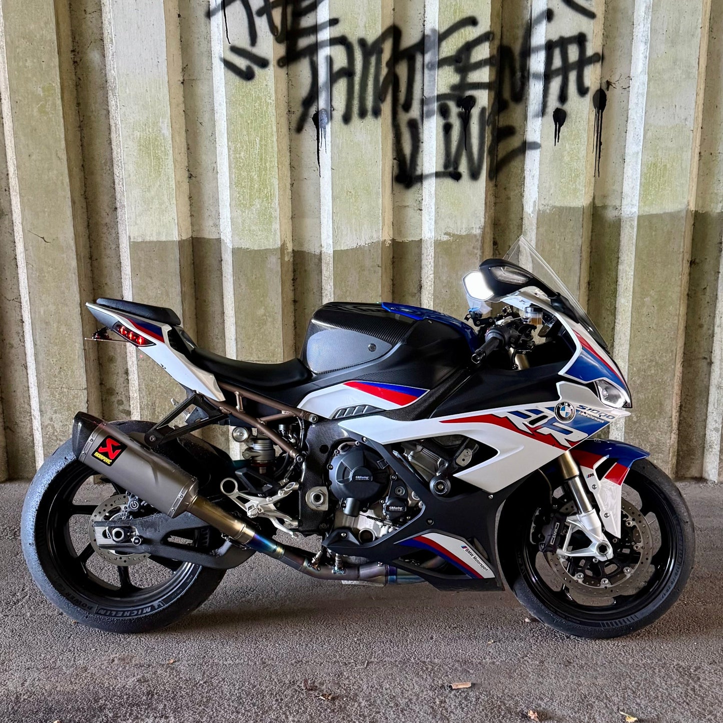 Motorcycle parked on a concrete surface with a corrugated metal wall in the background